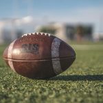 Close-up of a Wilson football on green grass in an outdoor sports setting, perfect for sports-themed visuals.